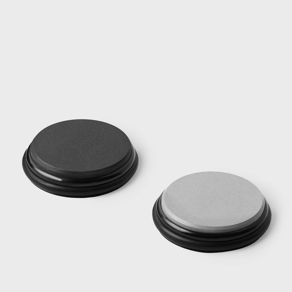 Two stacks of Tumbler Pro whetstone discs, one with dark black discs and the other with lighter discs and metal centers